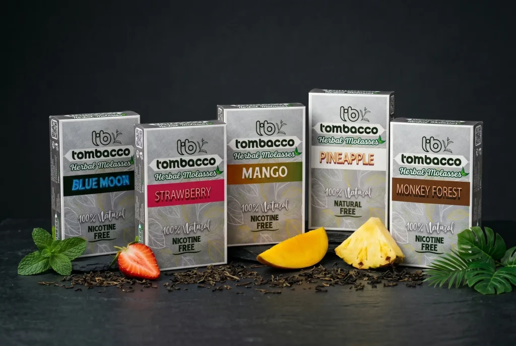 Five Tombacco product boxes lined up next to real dried tea leaves and fresh fruit. This flavourful, nicotine-free lineup is a fantastic option to consider when choosing between herbal or tobacco shisha.