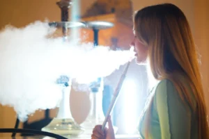 A shisha smoker enjoying a session while demonstrating how to manage nicotine level in shisha through the right tobacco choice and smoking pace.