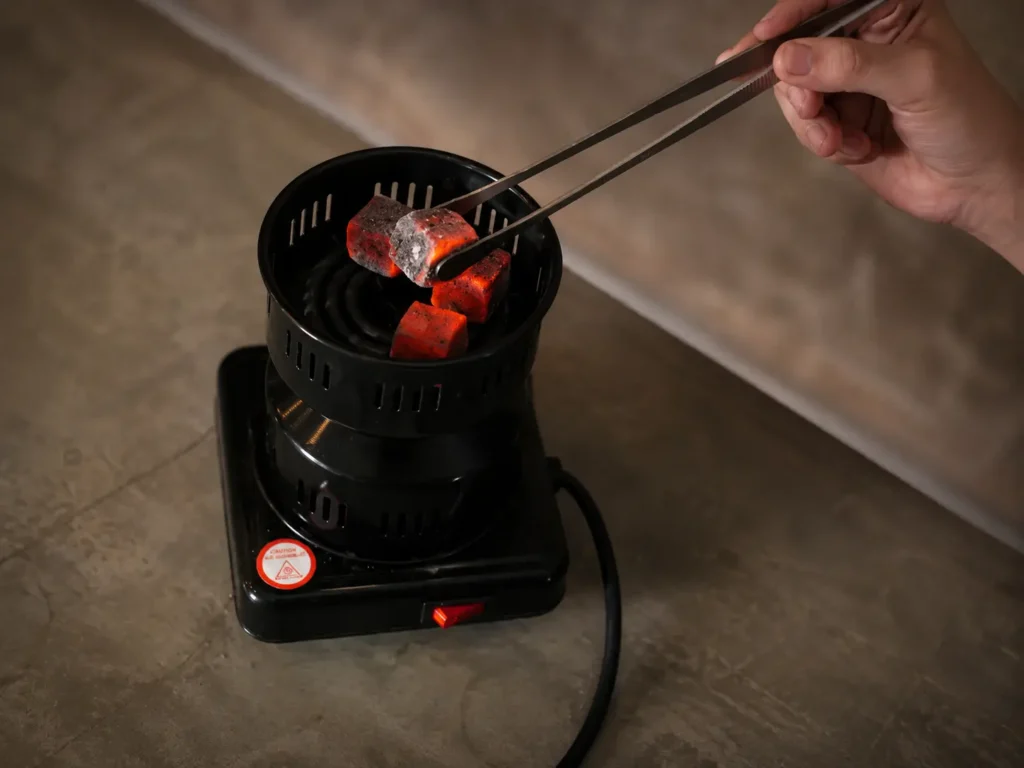 Lighting natural coconut charcoal on a burner before a shisha session