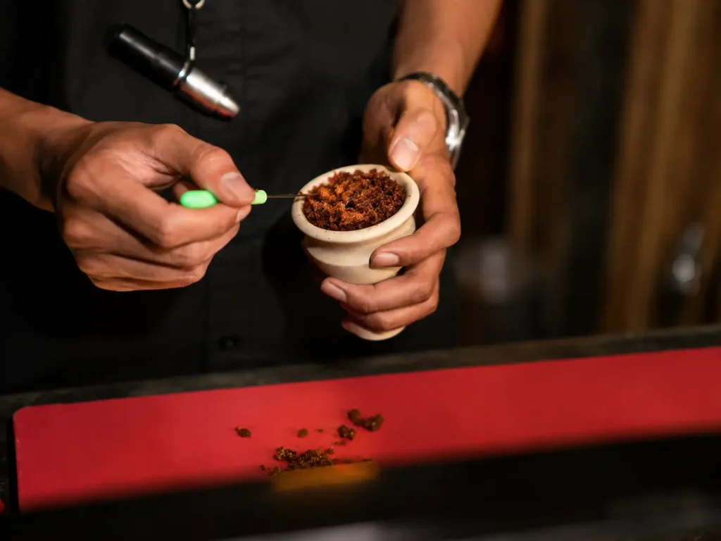 Preparing shisha tobacco by gently loosening and filling the bowl