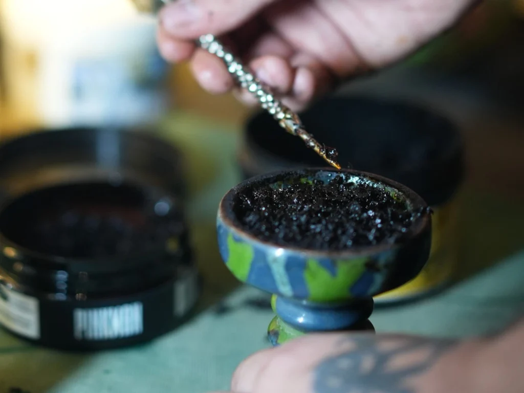 Preparing shisha tobacco in a bowl with the right packing method to help manage nicotine level in shisha and create a smoother smoking experience.